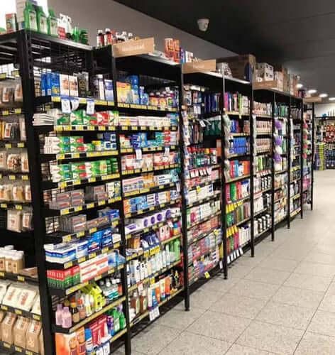 Store aisle with black metal shelves stocked with various packaged food and grocery items