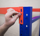 Hand tightening bolt on blue and red metal shelving unit in a warehouse or storage area