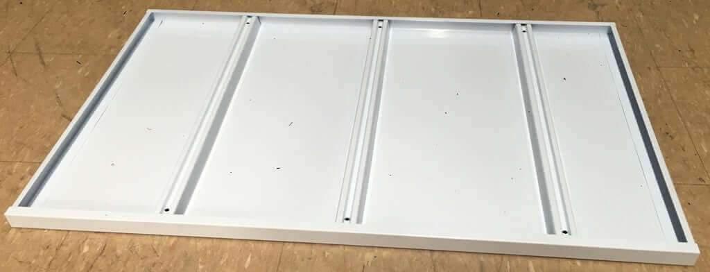 White metal heavy duty shelving deck with raised edges on wood floor